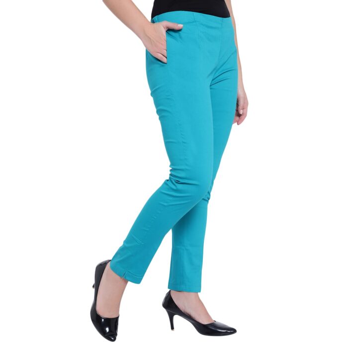 Close-up of a woman wearing a pair of teal-colored pants. Her hand is in the left pocket.